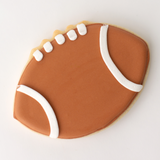 Football-shaped cookie with brown and white icing on a white background